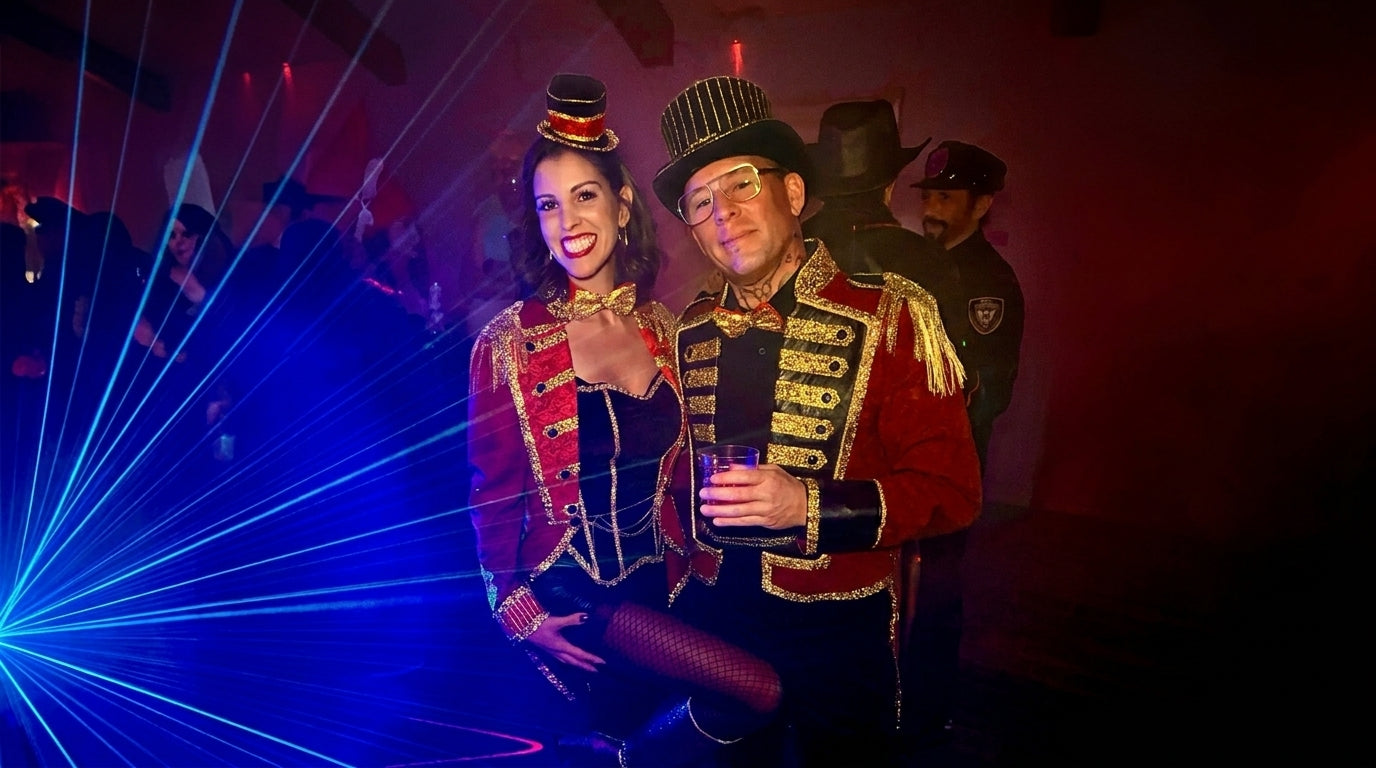 Designer Juliana and Kurt in matching luxury ringmaster jackets on a cinematic theater stage with dramatic spotlighting.